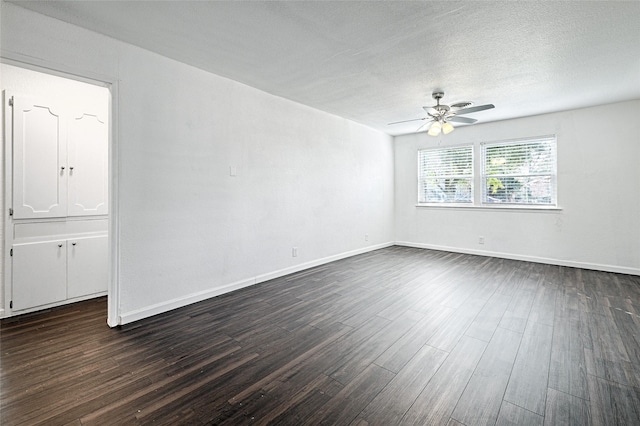 empty room featuring a ceiling fan, a textured ceiling, baseboards, and dark wood-type flooring