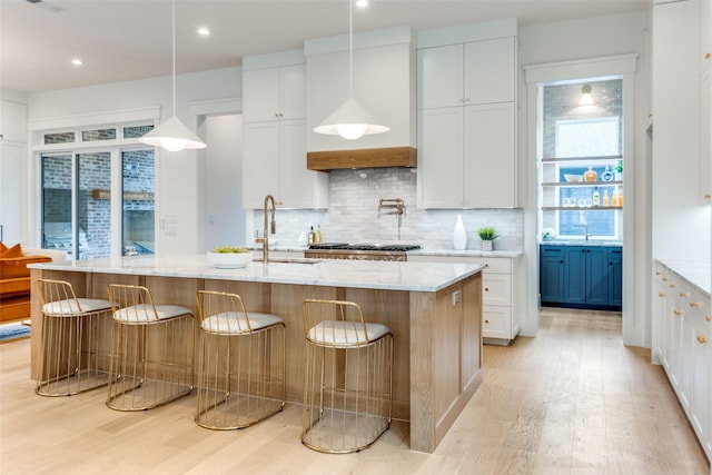 kitchen featuring white cabinetry, sink, and an island with sink