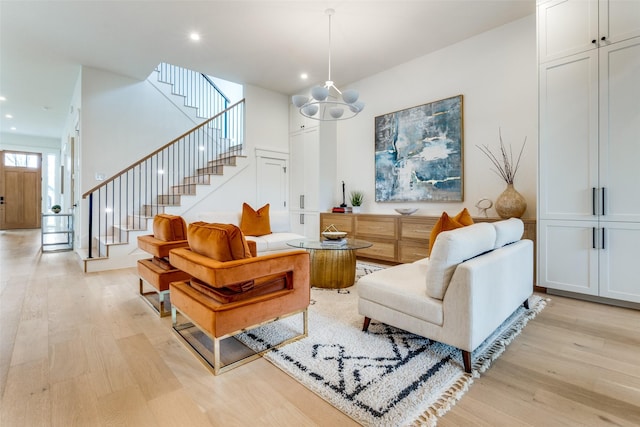 living room featuring a high ceiling, a notable chandelier, and light hardwood / wood-style flooring