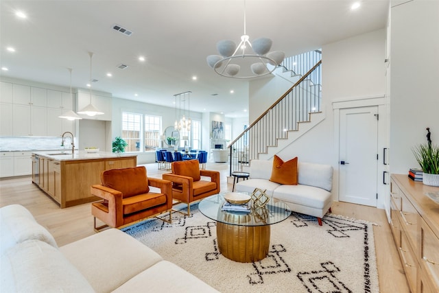 living room with a notable chandelier, sink, and light wood-type flooring