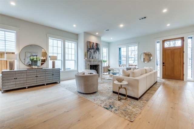 living room featuring a high end fireplace and light hardwood / wood-style flooring