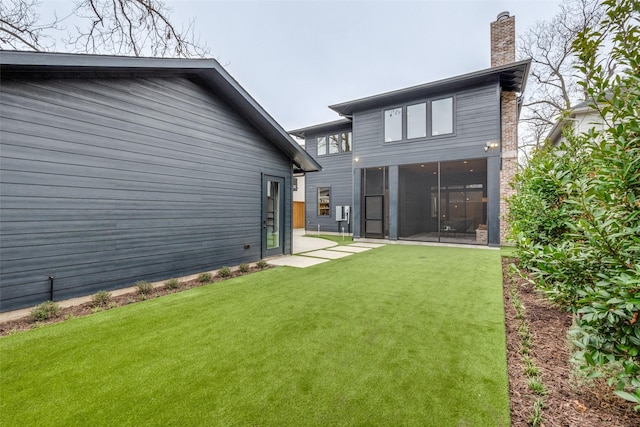 back of property with a patio, a sunroom, and a lawn