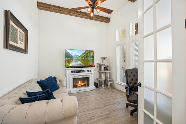 home office with ceiling fan, beam ceiling, and light hardwood / wood-style floors