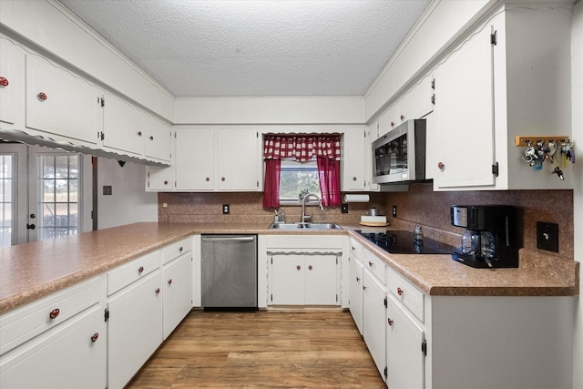 kitchen featuring appliances with stainless steel finishes, sink, white cabinets, decorative backsplash, and light hardwood / wood-style flooring