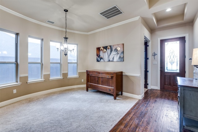 entrance foyer with crown molding, a chandelier, and dark carpet