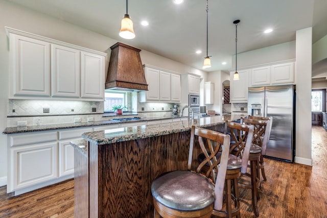 401 Devonshire Dr, Prosper, TX 75078 - kitchen featuring stainless steel appliances, custom exhaust hood, arched walkways, dark wood-style floors, and recessed lighting