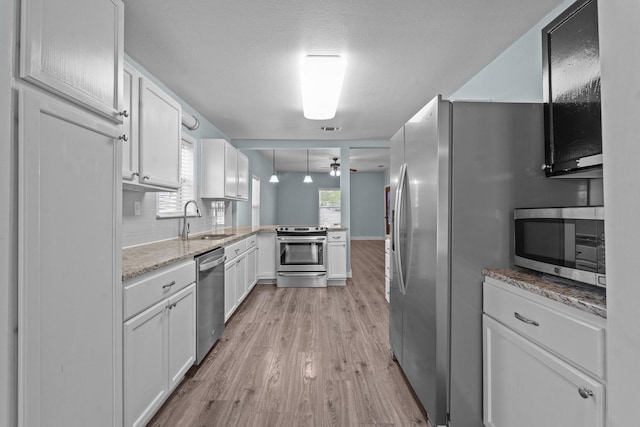119 Wheeler St, Weatherford, TX 76086 - kitchen with appliances with stainless steel finishes, a peninsula, ceiling fan, light wood finished floors, and a sink