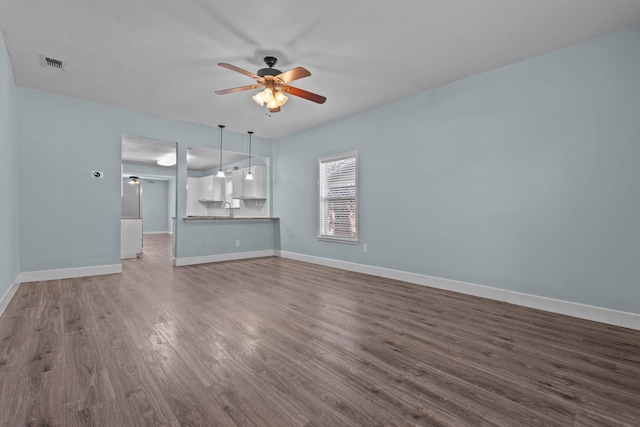 119 Wheeler St, Weatherford, TX 76086 - unfurnished living room featuring ceiling fan, dark wood finished floors, visible vents, a sink, and baseboards