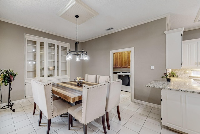 dining room featuring crown molding, washer and clothes dryer, a chandelier, and light tile patterned flooring