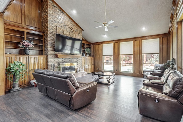 living room featuring a brick fireplace, wooden walls, a textured ceiling, and built in shelves