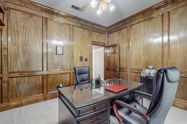 carpeted office space with ceiling fan, wooden walls, and a textured ceiling