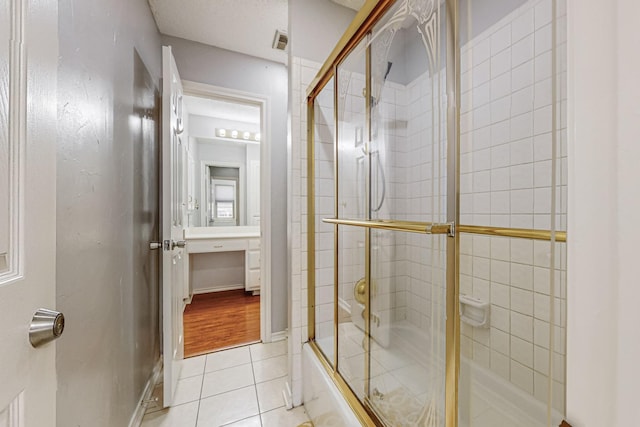 bathroom featuring tile patterned flooring and bath / shower combo with glass door