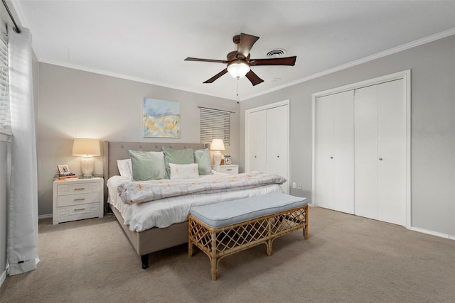 bedroom featuring crown molding, ceiling fan, light carpet, and two closets