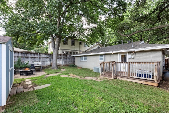 view of yard with cooling unit, a deck, and a fire pit