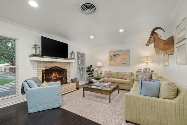 living room featuring hardwood / wood-style flooring, ornamental molding, and a brick fireplace