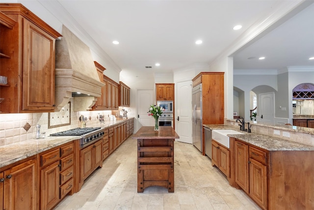 kitchen with a kitchen island, sink, built in appliances, light stone counters, and custom range hood