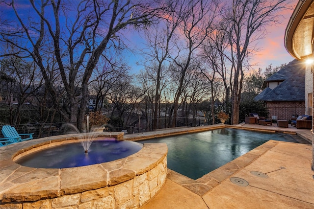 pool at dusk with pool water feature and a jacuzzi