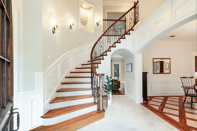 entryway with crown molding and a towering ceiling