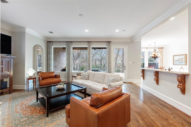 living room featuring crown molding, an inviting chandelier, and light wood-type flooring