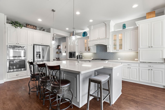 kitchen featuring white cabinetry, a center island with sink, a kitchen breakfast bar, and decorative light fixtures