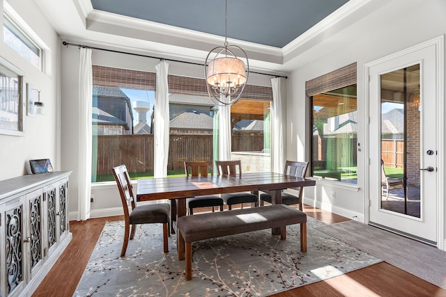 dining area with crown molding, a tray ceiling, dark hardwood / wood-style flooring, and a notable chandelier