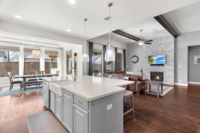 kitchen with dark wood-type flooring, sink, a kitchen island with sink, and hanging light fixtures