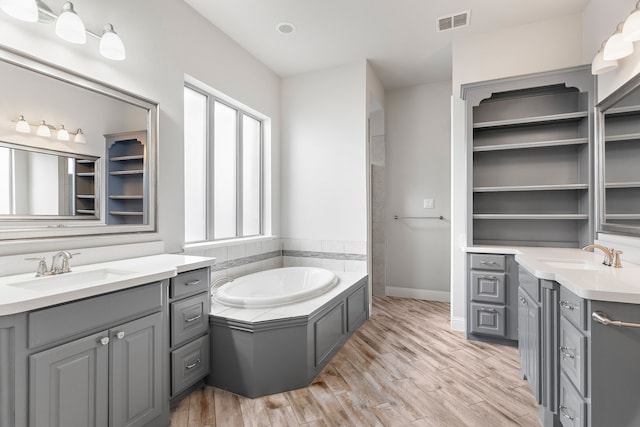 bathroom featuring vanity, a tub to relax in, and wood-type flooring