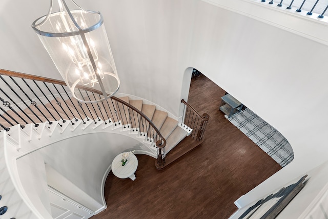 staircase with hardwood / wood-style flooring and a chandelier