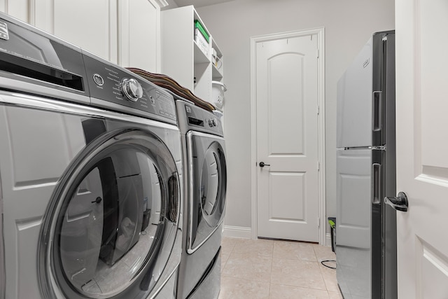 laundry room with independent washer and dryer and light tile patterned floors