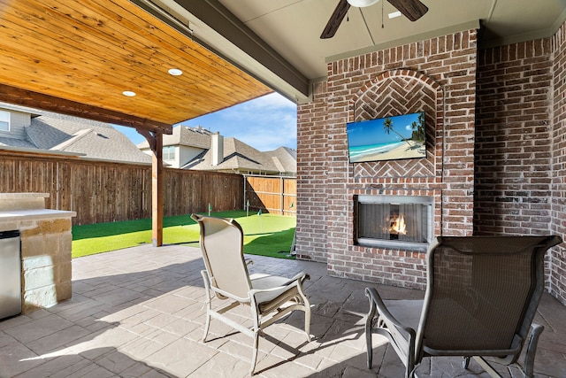 view of patio / terrace featuring an outdoor brick fireplace and ceiling fan