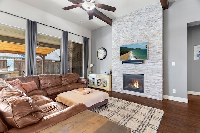 living room featuring beamed ceiling, a fireplace, dark hardwood / wood-style flooring, and ceiling fan