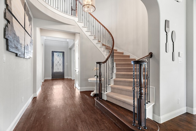 foyer with dark wood-type flooring and a towering ceiling