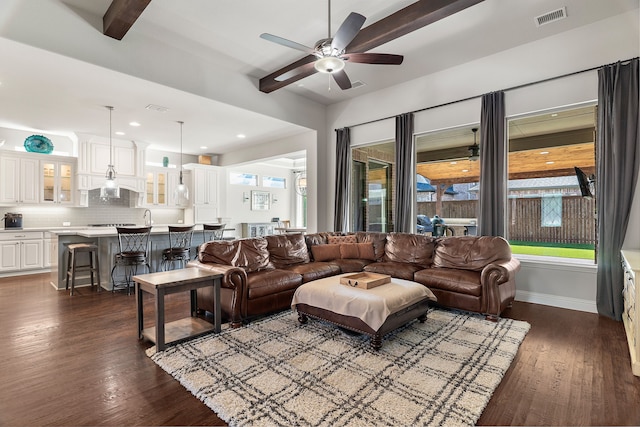 living room featuring beamed ceiling, ceiling fan, sink, and dark hardwood / wood-style flooring