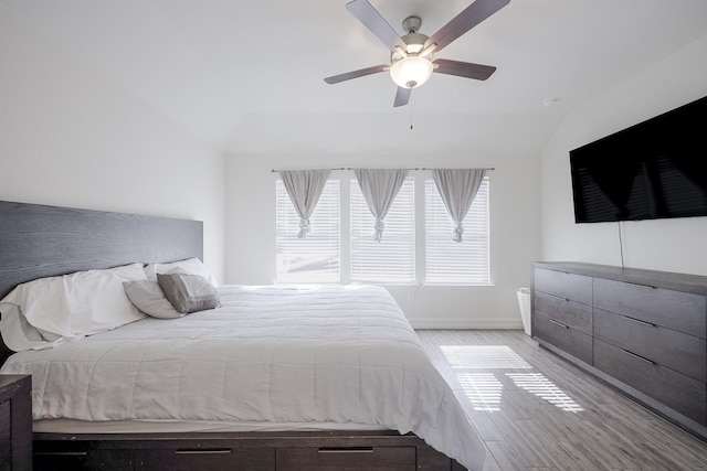 bedroom with ceiling fan, vaulted ceiling, and light hardwood / wood-style flooring