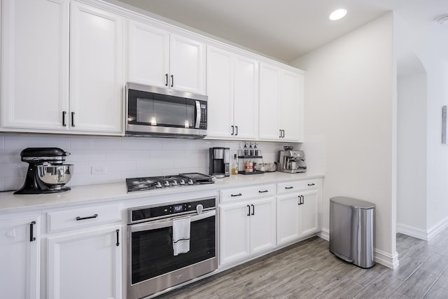 kitchen with stainless steel appliances, white cabinetry, tasteful backsplash, and light wood-type flooring