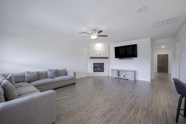 living room with hardwood / wood-style flooring, a stone fireplace, and ceiling fan