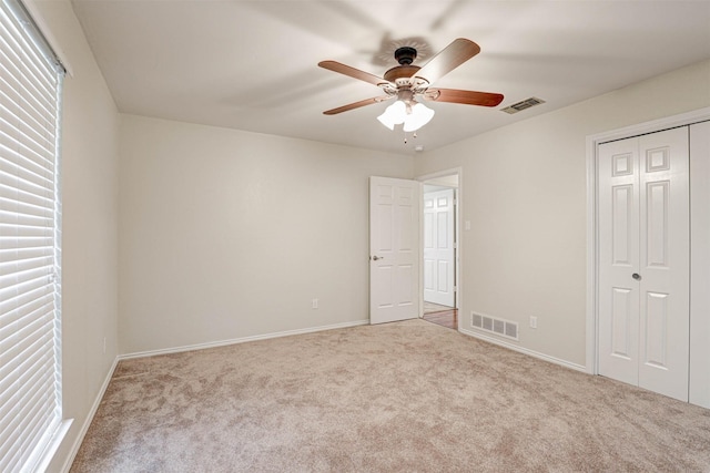 unfurnished bedroom with light colored carpet, a closet, and ceiling fan