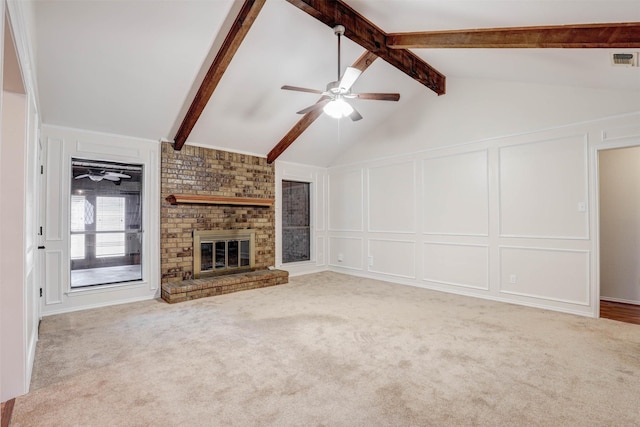 unfurnished living room featuring ceiling fan, a brick fireplace, light carpet, and vaulted ceiling with beams