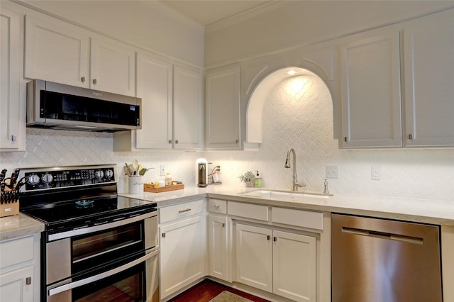 kitchen featuring stainless steel appliances, ornamental molding, tasteful backsplash, and white cabinetry