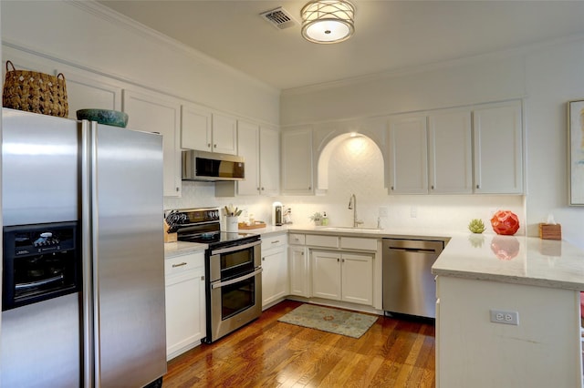 kitchen featuring appliances with stainless steel finishes, white cabinetry, sink, crown molding, and dark wood-type flooring