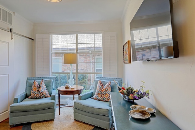 sitting room with ornamental molding, a barn door, and hardwood / wood-style floors