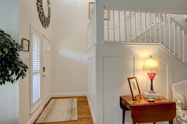 entryway with hardwood / wood-style floors and a towering ceiling