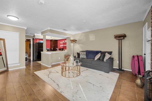 living room with ornamental molding, dark hardwood / wood-style floors, sink, and a textured ceiling