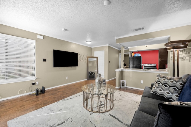 living room featuring ornamental molding, wood-type flooring, and a textured ceiling