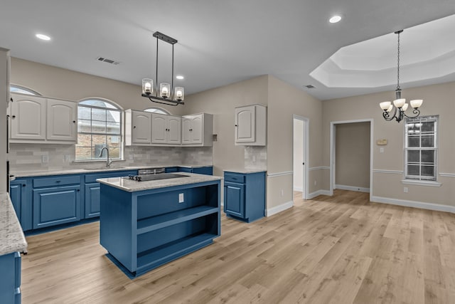 kitchen with pendant lighting, sink, blue cabinets, a notable chandelier, and a kitchen island