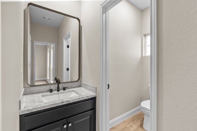 bathroom featuring vanity, hardwood / wood-style flooring, and toilet