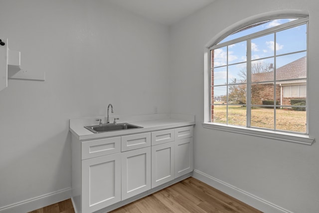 interior space with sink, white cabinets, and light wood-type flooring