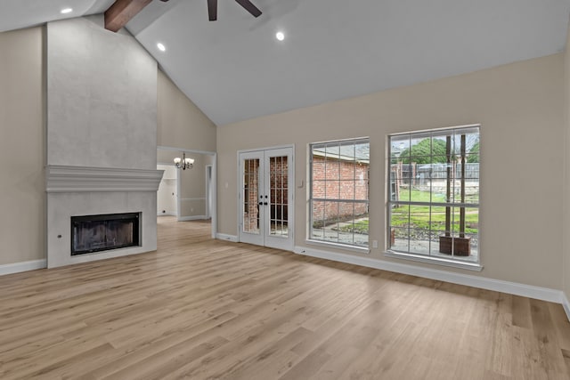 unfurnished living room featuring high vaulted ceiling, light wood-type flooring, a tile fireplace, beam ceiling, and ceiling fan with notable chandelier