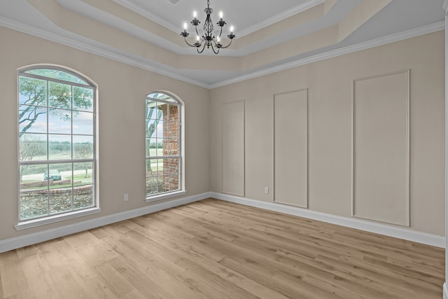 unfurnished room featuring a chandelier, a raised ceiling, and a wealth of natural light