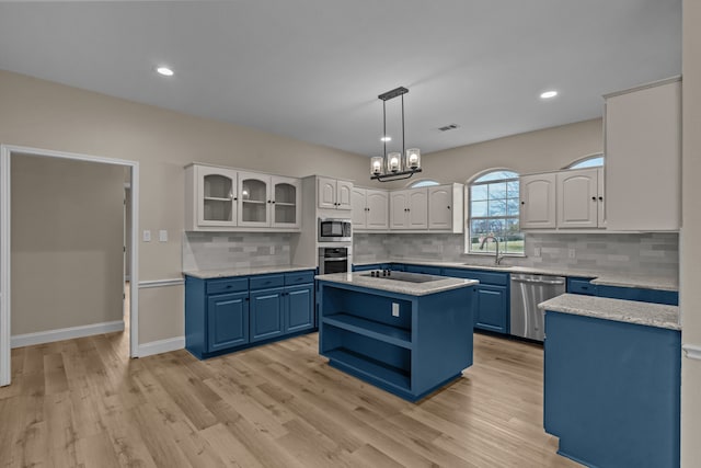 kitchen with appliances with stainless steel finishes, a center island, white cabinets, and blue cabinetry